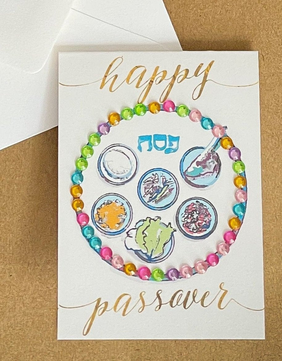 this is a mini note card on a craft paper gift bag with a white envelope and a black marker , the card has Happy Passover with a decorated gold Sedar plate