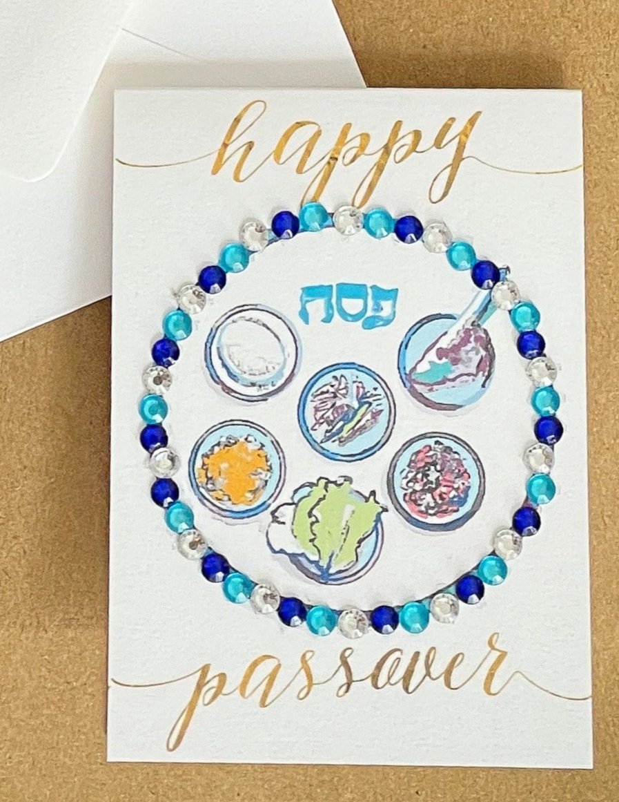 this is a mini note card on a craft paper gift bag with a white envelope and a black marker , the card has Happy Passover with a decorated gold Sedar plate