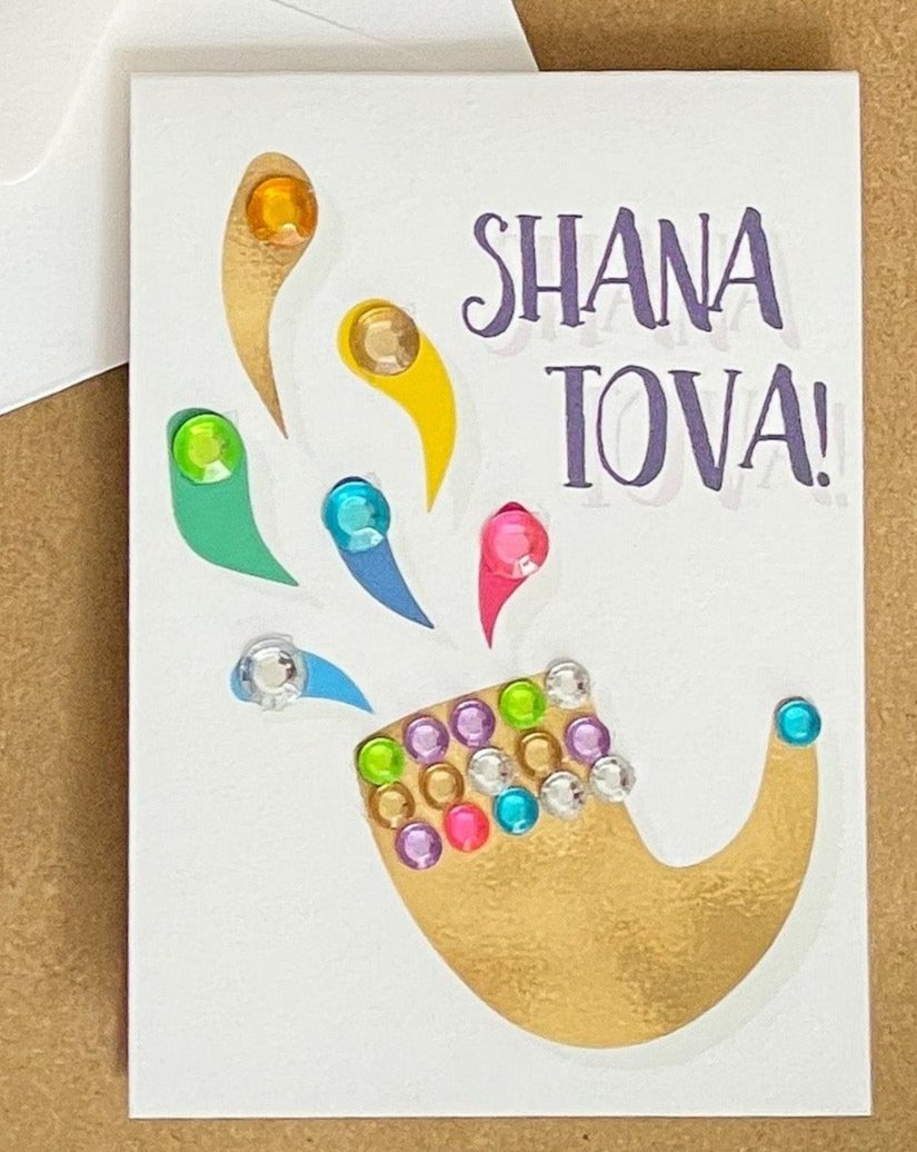 this is a mini note card on a craft paper gift bag with a white envelope and a black marker , the card says Shana Tova in English with a shofar